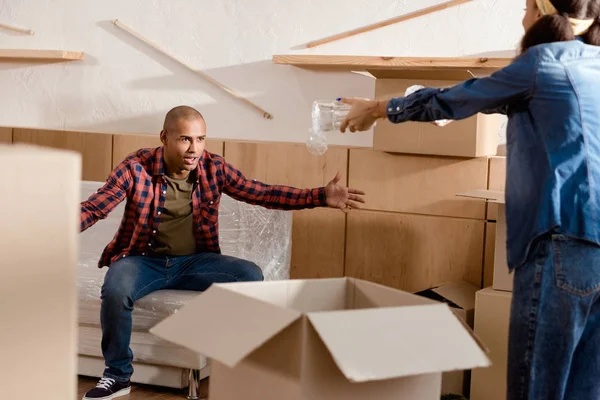 Couple afro-américain emballage et querelle dans un nouvel appartement avec des boîtes en carton — Photo de stock