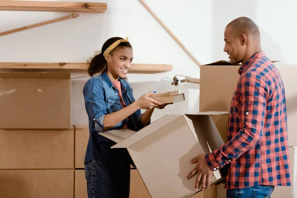 Happy african american couple unpacking books in new home — Stock Photo