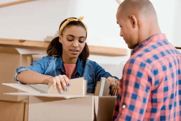 Young african american couple unpacking books in new apartment — Stock Photo