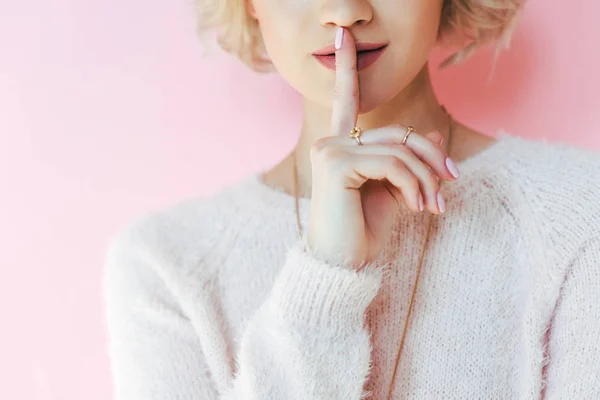 Cropped shot of young woman gesturing for silence isolated on pink — Stock Photo