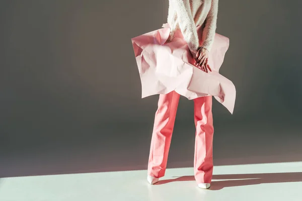 Cropped shot of stylish girl posing with pink crumpled paper on waist in studio — Stock Photo