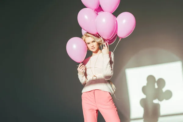 Красива стильна молода жінка позує з рожевими кульками в студії — стокове фото