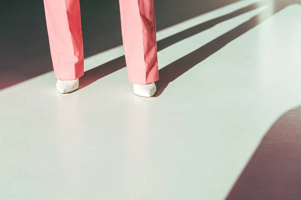 Cropped view of fashionable woman in pink trousers and white hills — Stock Photo
