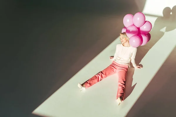 Schöne stilvolle Frau sitzt mit rosa Luftballons — Stockfoto