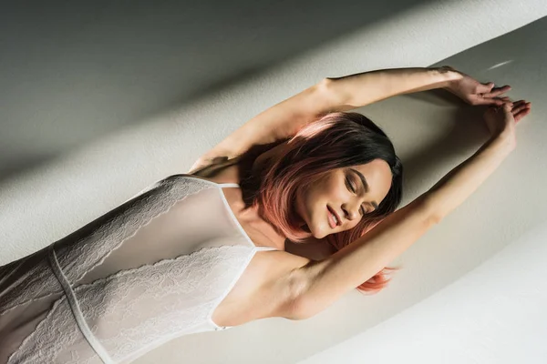 Séduisante femme aux cheveux roses couché dans un body en dentelle blanche — Photo de stock