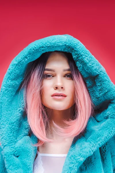 Молода модель з рожевим волоссям позує в модній синій шубці, ізольована на рожевому — стокове фото