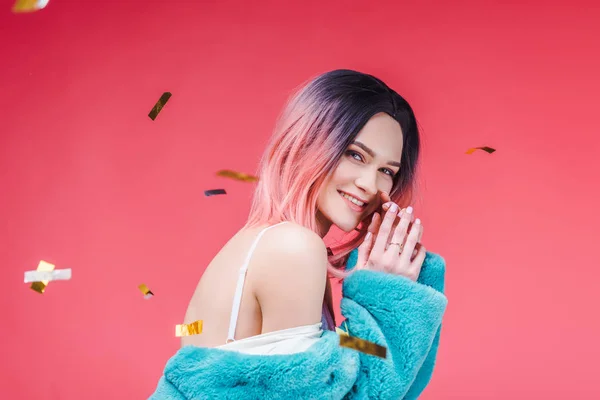 Menina bonita feliz posando em casaco de pele azul, isolado em rosa com confete — Fotografia de Stock