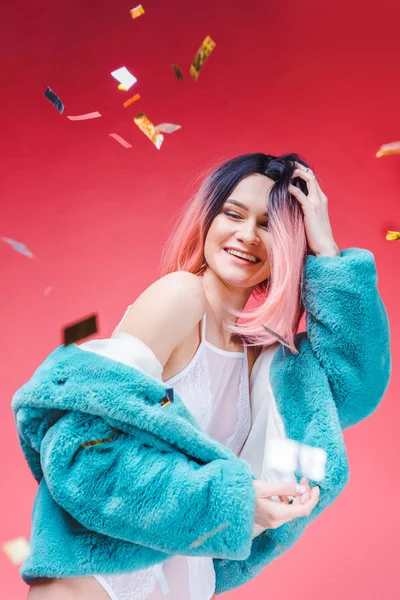 Fröhliches modisches Mädchen im blauen Pelzmantel, vereinzelt auf rosa mit Konfetti — Stockfoto