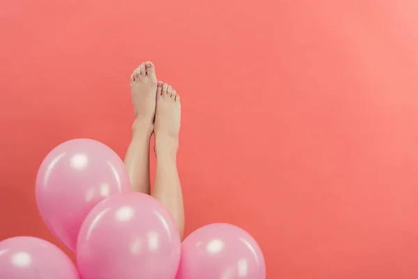 Vista cortada de pernas femininas com balões rosa, isolado em vermelho — Fotografia de Stock