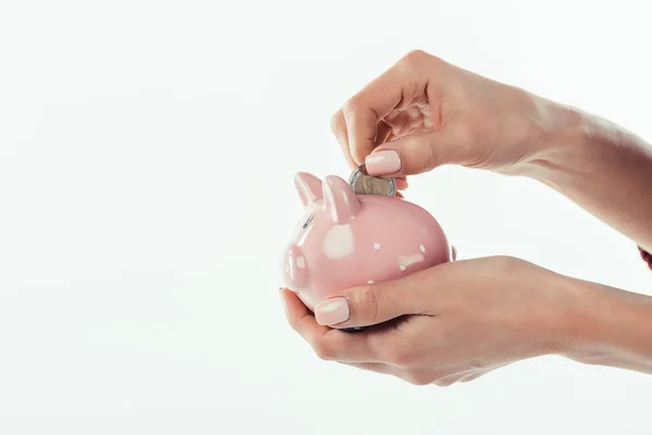 Cropped view of woman putting coin into little piggy bank, isolated on white — Stock Photo