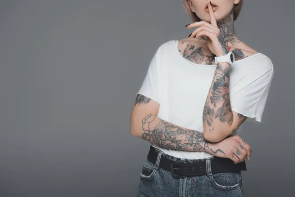 Cropped shot of young woman with tattoos gesturing for silence isolated on grey — Stock Photo