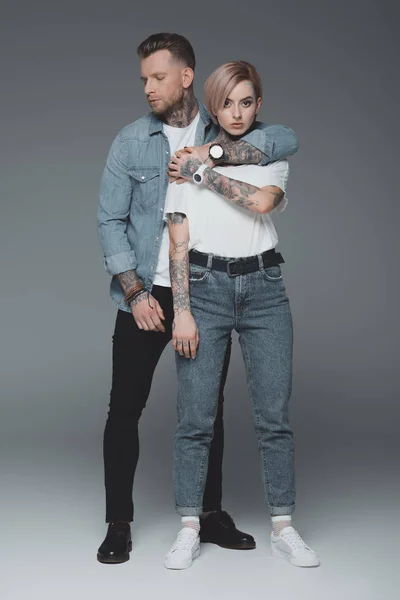 Повний вигляд стильної молодої пари в любові обіймається на сірому — стокове фото