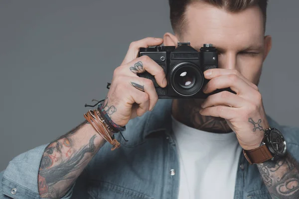 Élégant jeune homme tatoué photographie avec appareil photo isolé sur gris — Photo de stock