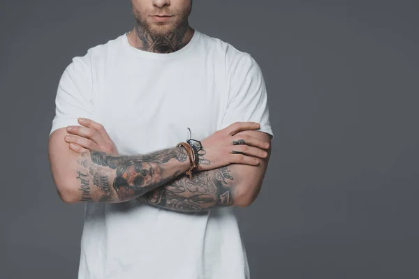 Cropped shot of young man with tattoos standing with crossed arms isolated on grey — Stock Photo