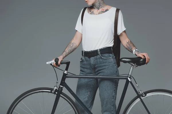 Recortado disparo de chica con estilo con tatuajes de pie con bicicleta aislada en gris - foto de stock