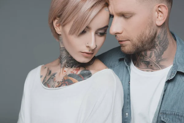 Красива молода татуйована пара в любові позує разом ізольовано на сірому — стокове фото