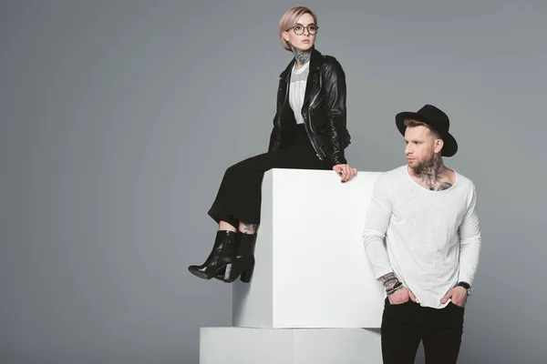 Elegante joven tatuado pareja posando juntos aislado en gris - foto de stock