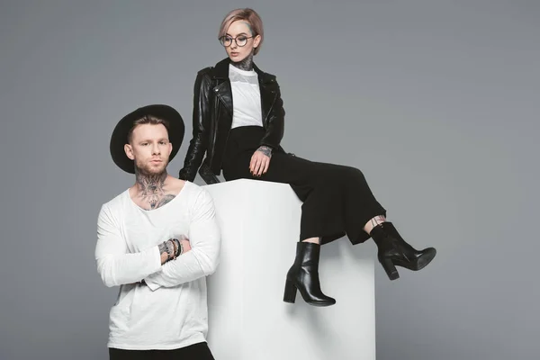 Schöne stylische junge Paar mit Tätowierungen posiert zusammen isoliert auf grau — Stockfoto