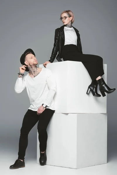Vista completa de la hermosa pareja joven y elegante con tatuajes posando juntos en el estudio - foto de stock