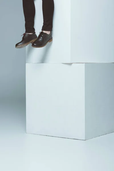 Cropped view of fashionable man in shoes on white cubes, isolated on grey — Stock Photo