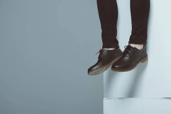 Обрезанный вид человека в модных туфлях на белых кубиках, изолированных на сером — стоковое фото