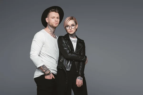 Elegante pareja tatuada posando juntos, aislado en gris - foto de stock