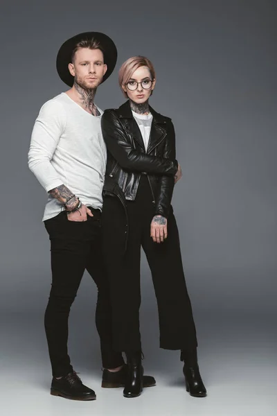 Pareja tatuada de moda posando juntos, aislados en gris - foto de stock