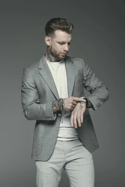 Handsome stylish businessman looking at watch, isolated on grey — Stock Photo