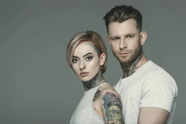 Portrait of tattooed couple posing together, isolated on grey — Stock Photo