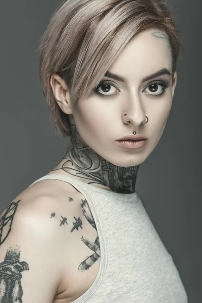 Красива татуйована дівчина, ізольована на сірому — стокове фото