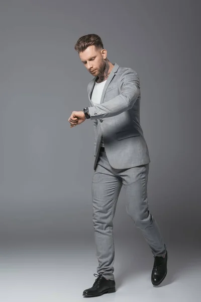 Handsome hurrying businessman looking at watch, isolated on grey — Stock Photo