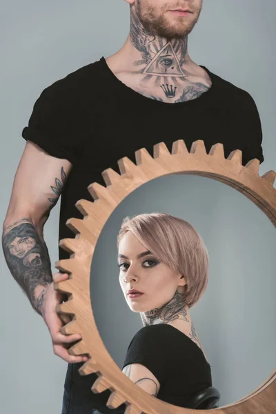 Tattooed man holding mirror with reflection of his girlfriend, isolated on grey — Stock Photo