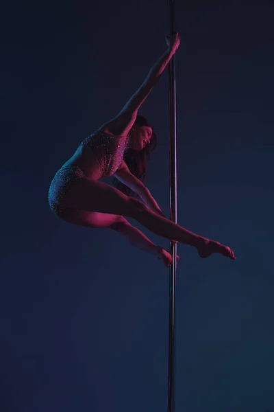 Beautiful athletic young woman dancing with pole on blue — Stock Photo