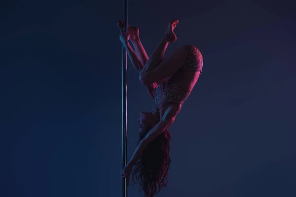 Upside down of sporty young woman dancing with pole on blue — Stock Photo