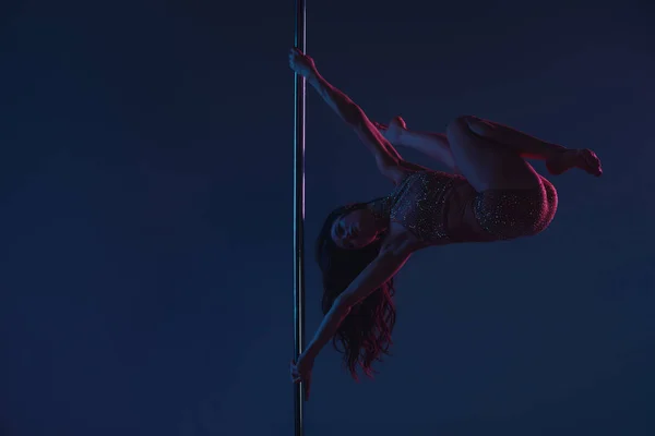 Vista completa de la joven atlética flexible bailando con poste en azul - foto de stock