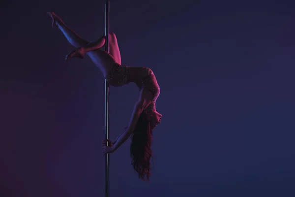 Beautiful sensual flexible girl exercising with pole on blue — Stock Photo