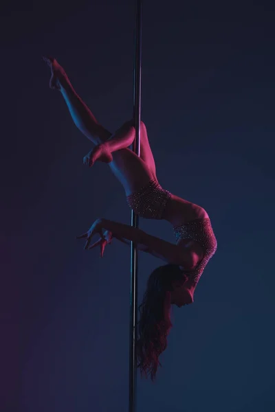 Belle jeune femme flexible faisant de l'exercice avec poteau sur bleu — Photo de stock