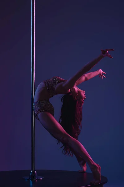Flexible athletic girl dancing with pole on blue — Stock Photo