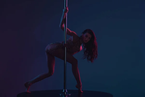 Schöne junge Pole-Tänzerin blickt in die Kamera auf blau — Stockfoto
