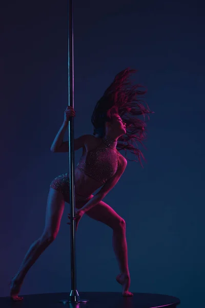 Seductive athletic woman dancing with pole on blue — Stock Photo