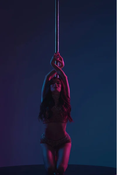 Beautiful seductive female dancer posing with pole on blue — Stock Photo