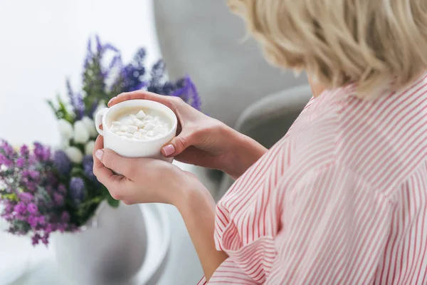 Vista cortada de mulher loira segurando copo de cappuccino com marshmallow — Fotografia de Stock