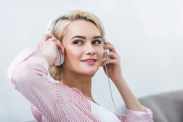 Chica rubia escuchando música con auriculares - foto de stock