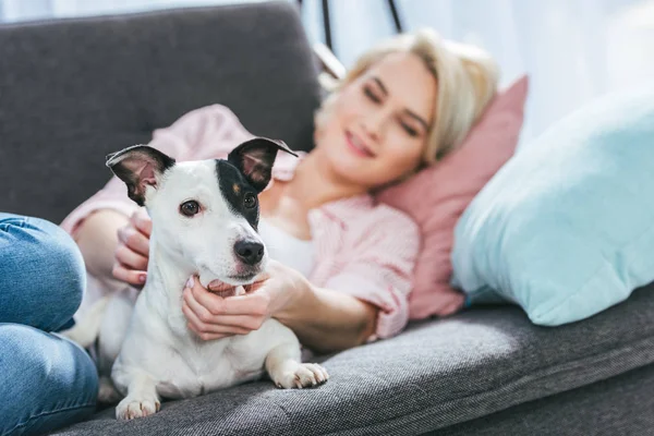 Blonde femme avec jack russell terrier chien couché sur canapé — Photo de stock
