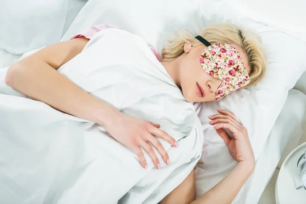 Блондинка в маске для сна на кровати — стоковое фото