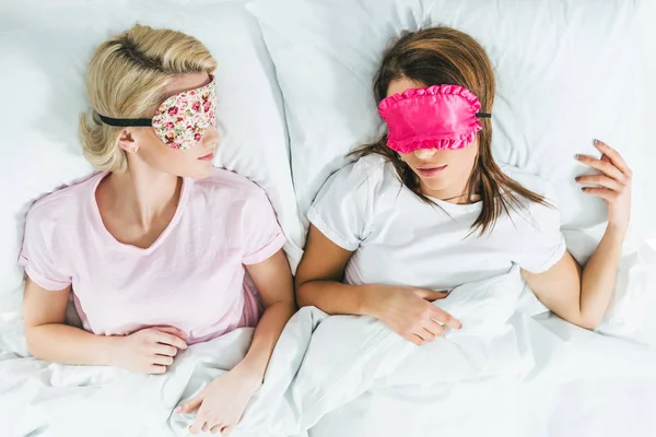 Vista dall'alto di giovani ragazze che dormono in maschera sul letto — Foto stock