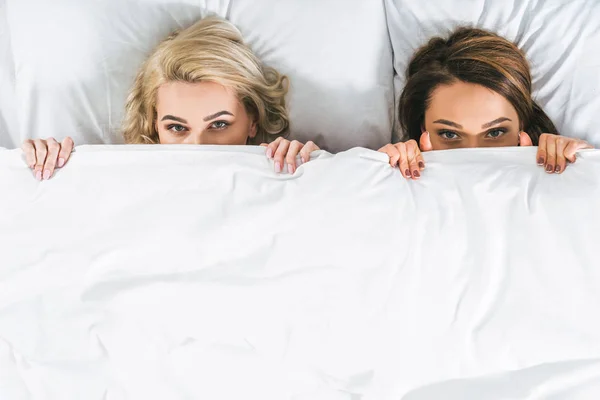 Vue de dessus des femmes attrayantes couchées dans le lit — Photo de stock