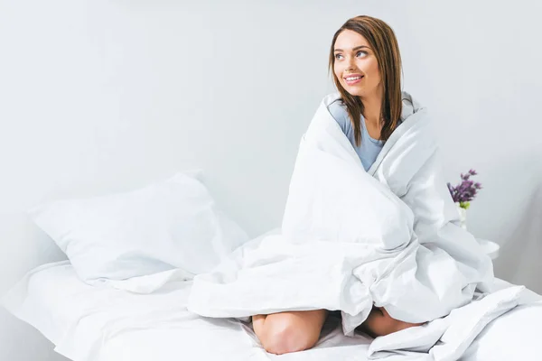 Attraktives lächelndes Mädchen, das morgens auf dem Bett sitzt — Stockfoto