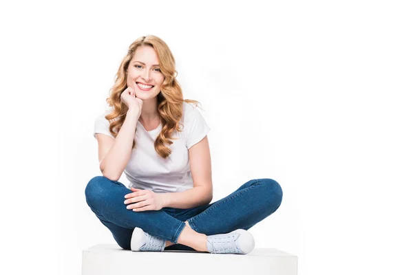 Lächelnde Frau sitzt auf weißem Würfel — Stockfoto