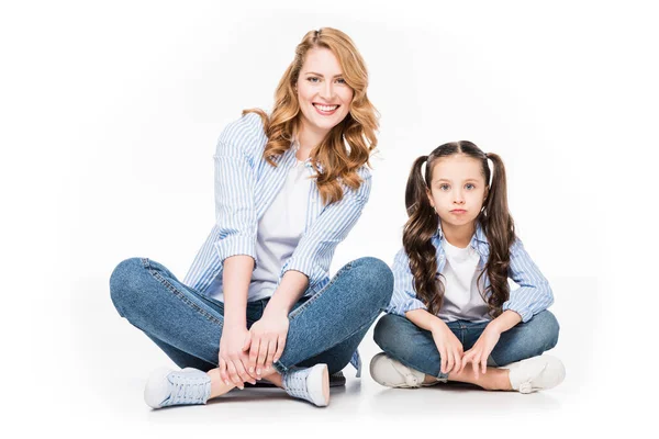 Porträt einer lächelnden Mutter und ihrer Tochter in Jeanskleidung, die isoliert auf weiß in die Kamera blickt — Stockfoto
